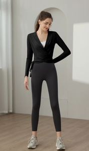 Modern fitness outfit featuring a black wrap-around yoga top and charcoal high-waist leggings