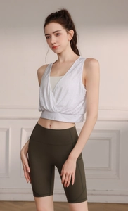 Detail view of white V-neck jacquard sports top with cross-layered hem and green biker shorts