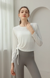 Detail of white long sleeve yoga top with adjustable side drawstring and ruched texture