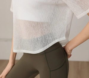 Détail du haut de sport en mesh blanc et legging vert olive avec poches latérales