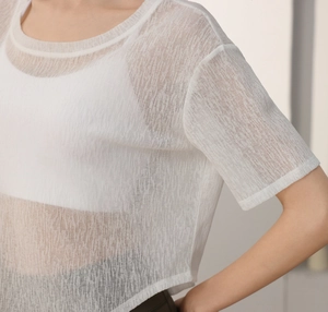 Détail du haut de yoga en maille blanche montrant le tissu transparent et le col rond