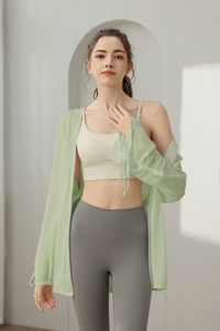 Detail of light green yoga cover-up featuring sheer fabric and adjustable drawstring cuffs
