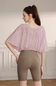 Detail of pink mesh yoga top with batwing sleeves and high waist brown sports shorts