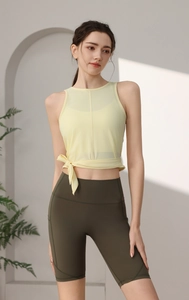 Detail eines hellgelben Yoga-Oberteils mit Knotentaille und grünen High-Waist-Shorts