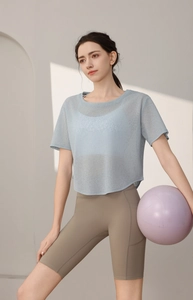 Détail du haut de yoga bleu clair avec short cycliste kaki et ballon de gymnastique