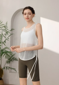 Detail of white mesh yoga tank top with side-tie closure and emerald green biker shorts
