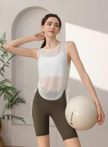 Detail of white mesh yoga tank top with side ties and green cycling shorts on model
