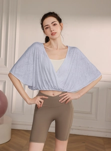 Detail of light blue batwing sleeve yoga cover up and white sports vest on female model