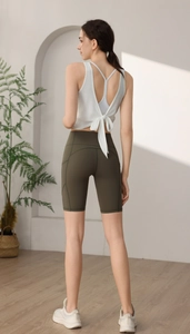 Detail von weißem Yoga-Top mit Rückenschleife und grüner High-Waist Fitness-Shorts