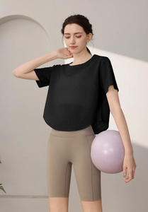 Détail du t-shirt de sport noir ample et du short de yoga beige sur un mannequin femme