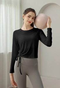 Detail view of the adjustable side drawstring on this black long sleeve yoga training top