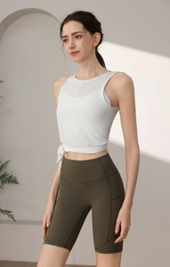 Detail des weißen Yoga-Oberteils zum Binden und olivgrüner Sport-Shorts am Modell