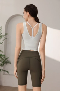 Detailansicht eines rückenfreien weißen Yoga-Tops kombiniert mit olivgrüner Fitness-Shorts