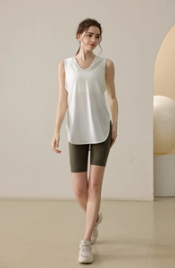 Detail showing white sleeveless hooded vest with rounded hem and green cycling shorts