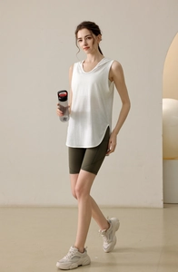 Detail view of women white hooded sport vest with side slits and olive green biker shorts