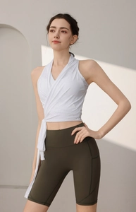 Dettaglio del gilet yoga bianco a incrocio e pantaloncini biker a vita alta verde oliva