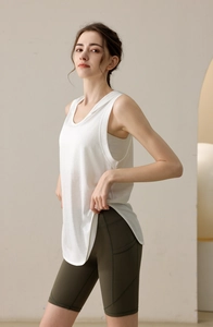 Detail view of white loose sports vest with large armholes and olive high waist cycling shorts