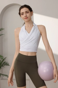 Dettaglio del top yoga bianco con allacciatura al collo e shorts fitness verde oliva