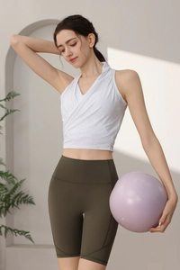 Dettaglio del top da yoga in maglia bianca e degli shorts fitness a vita alta verde oliva