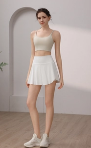 Détail d'une jupe de tennis plissée à taille haute blanche et débardeur de yoga beige