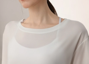 Detailed view of the breathable round neck sheer fabric on a loose white yoga top
