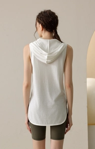 Rear view of loose white hooded sports tank top paired with olive green biker shorts