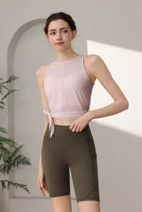 Detail von hellrosa Mesh-Yoga-Oberteil mit seitlicher Schleife und grünen Shorts
