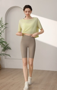 Detail of loose fit pale yellow tencel yoga shirt and brown pocket biker shorts