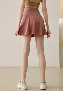 Détail de la taille haute croisée et de l'ourlet plissé de la jupe-short de sport rose