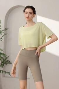 Detail of light yellow loose workout top paired with taupe high waist yoga shorts