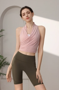 Dettaglio del top yoga incrociato rosa e dei pantaloncini da ciclista a vita alta verde scuro