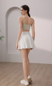 Seitenansicht von Tennisrock mit hoher Taille und beigem, kurzem Sport-Oberteil
