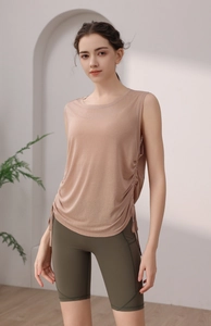 Detail view of apricot yoga vest with side drawstring and olive green high waist shorts