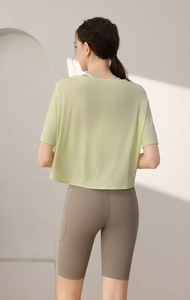 Back view of a loose short-sleeve green t-shirt with brown yoga shorts in an indoor setting