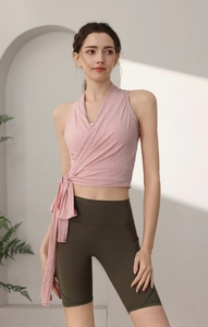 Dettaglio del top da yoga rosa a incrocio con lacci e pantaloncini verdi a vita alta