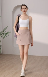 Dettaglio gonna da tennis rosa polvere con tasche laterali e reggiseno sportivo bianco abbinato