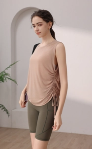 Detail of light camel tank top with side drawstrings and green yoga shorts with pockets