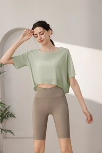Detail of light green loose sports crop top and khaki high waist cycling shorts for women
