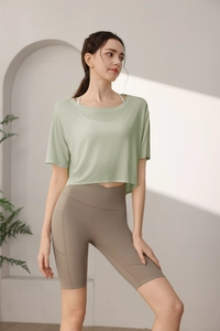 Detail of sage green loose sports top and high waisted yoga shorts with pockets