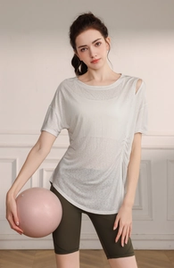 Détail du haut de yoga blanc en tencel avec découpe à l'épaule et design plissé sur le côté