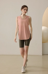 Close-up of pink sleeveless hooded workout top with curved hem and olive cycling shorts