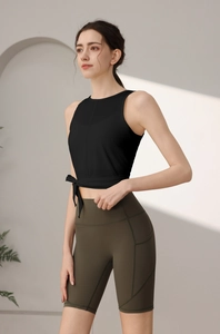Detail eines schwarzen Yoga-Tops mit Seitenknoten und grüner High-Waist Fitness-Shorts