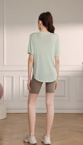 Vue arrière du haut de yoga vert clair transparent avec ourlet incurvé et short de cycliste
