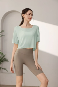 Close-up of mint green tencel workout top with brown high waist yoga shorts and pockets