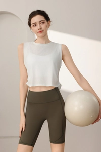Dettaglio di un top corto bianco e pantaloncini da ciclista a vita alta oliva per yoga