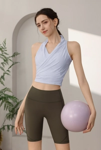 Dettaglio del top da yoga azzurro e pantaloncini sportivi verde oliva con palla da yoga