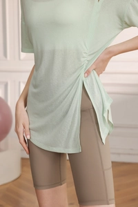 Détail du haut de yoga vert clair montrant la fente latérale et la texture plissée