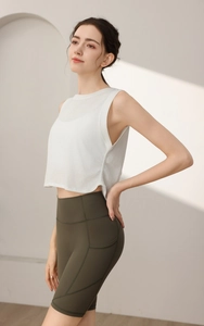 Dettaglio del top sportivo bianco senza maniche con spacco laterale e pantaloncini olive