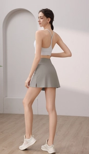 Detail von graugrünem Sport-Hosenrock mit Seitenschlitz und weißem Yoga-BH-Top