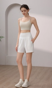 Detail view of high-waisted white yoga shorts with side pockets and a beige sports bra set